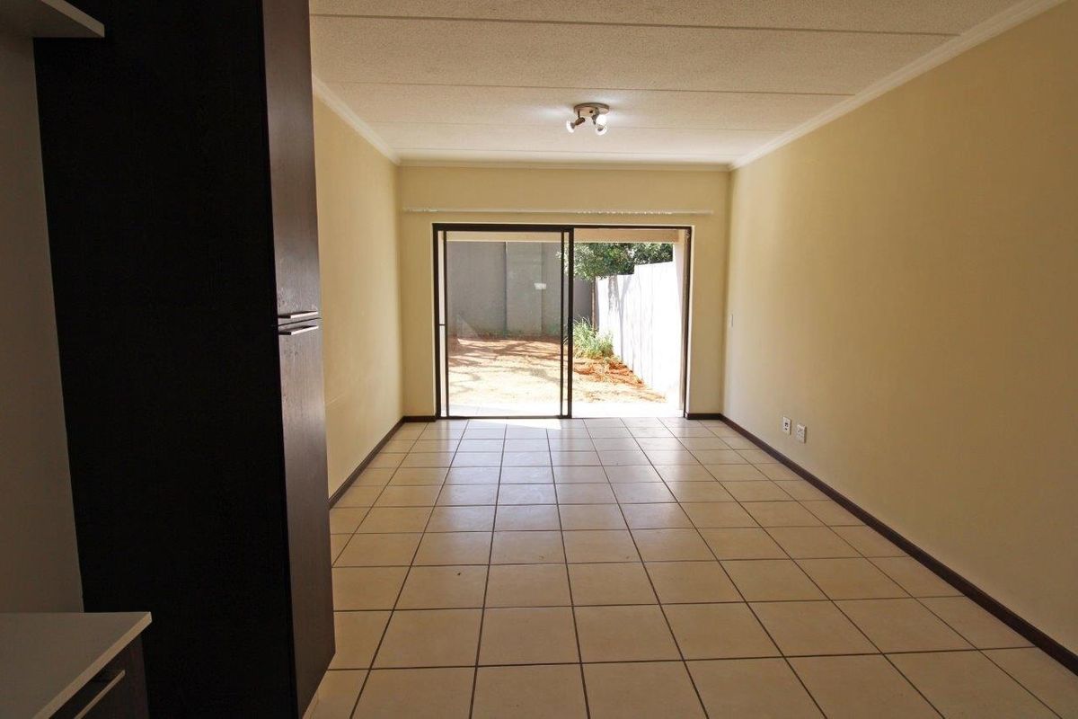 An empty living room featuring tiled flooring and a sliding glass door providing access to an outdoor area.