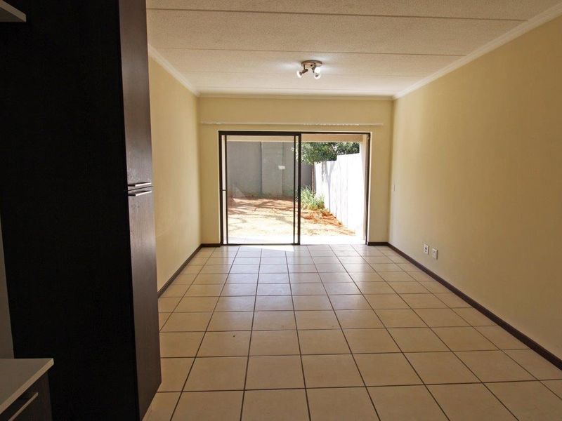 An empty living room featuring tiled flooring and a sliding glass door providing access to an outdoor area.