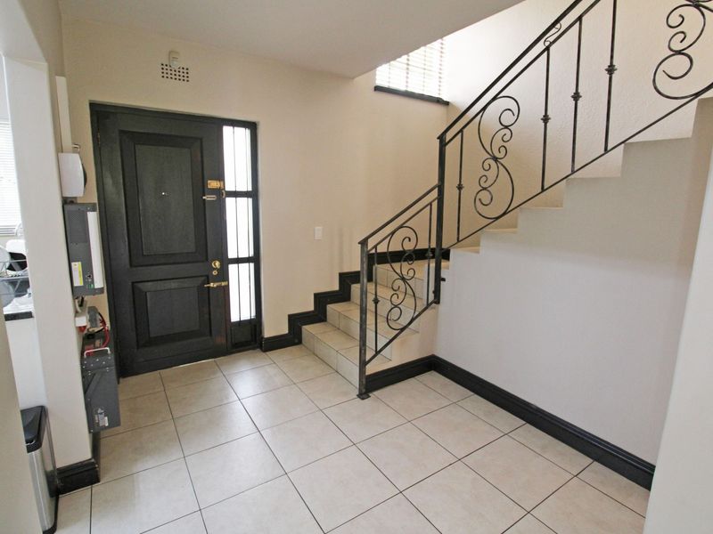 Bright entrance foyer featuring tiled flooring, a solid wood front door with side light, and a decorative wrought iron staircase railing.