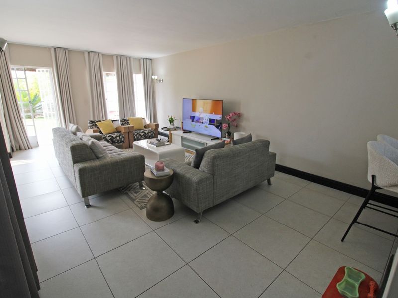 A spacious living room featuring large format floor tiles and glass sliding doors that provide ample natural light and access to the outdoors.