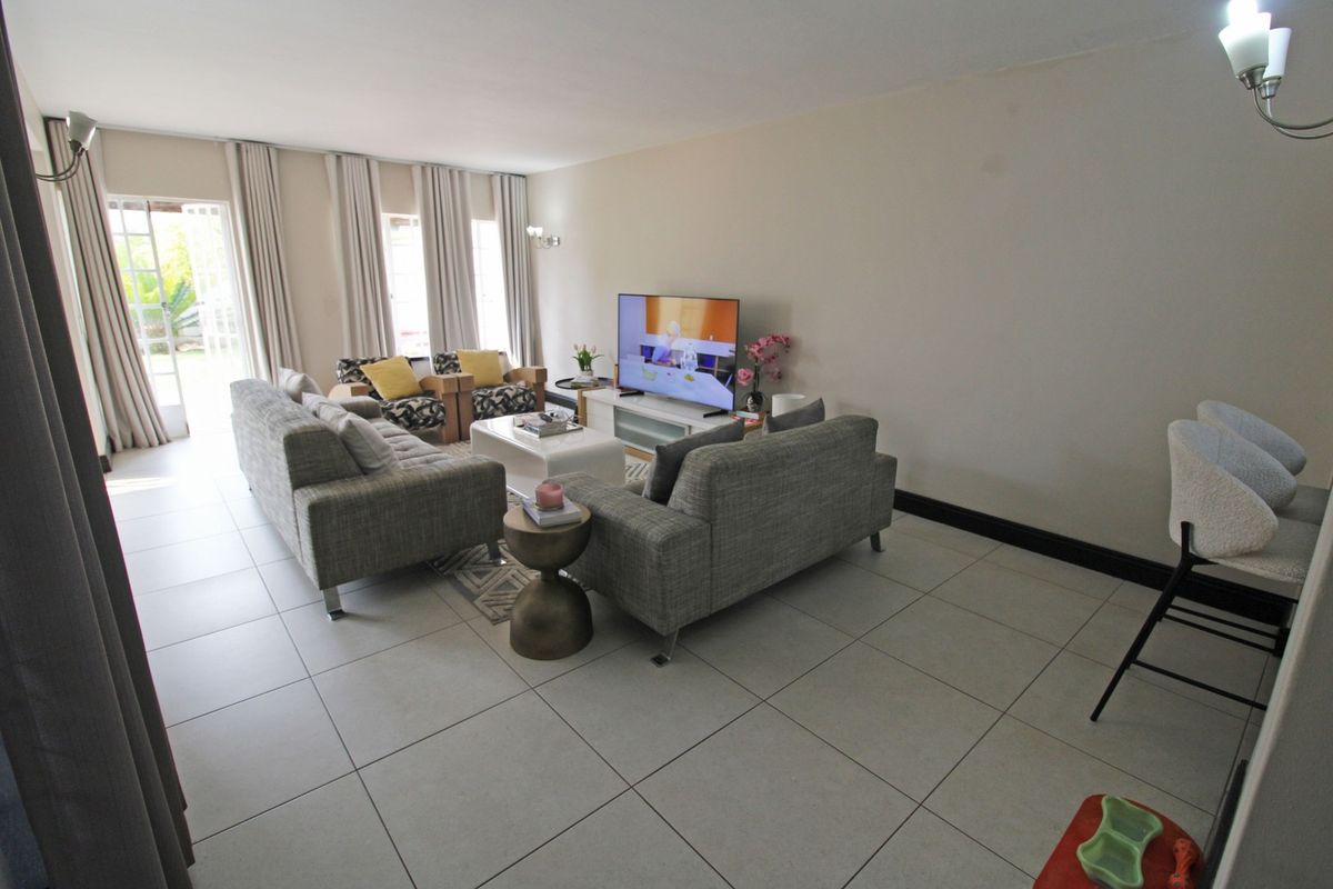A spacious living room featuring large format floor tiles and glass sliding doors that provide ample natural light and access to the outdoors.