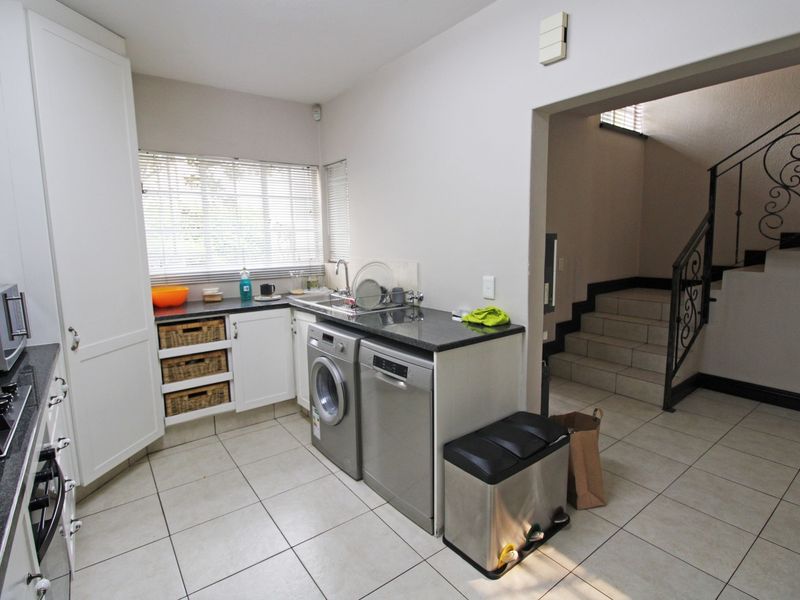 Functional scullery area featuring built-in cabinetry, granite countertops, and tiled flooring, with direct access to the staircase.