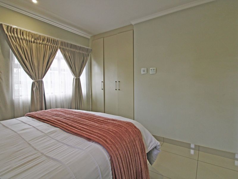 A well-maintained bedroom featuring neutral tiled flooring, built-in cupboards, and decorative cove cornicing, offering a clean and functional living space.