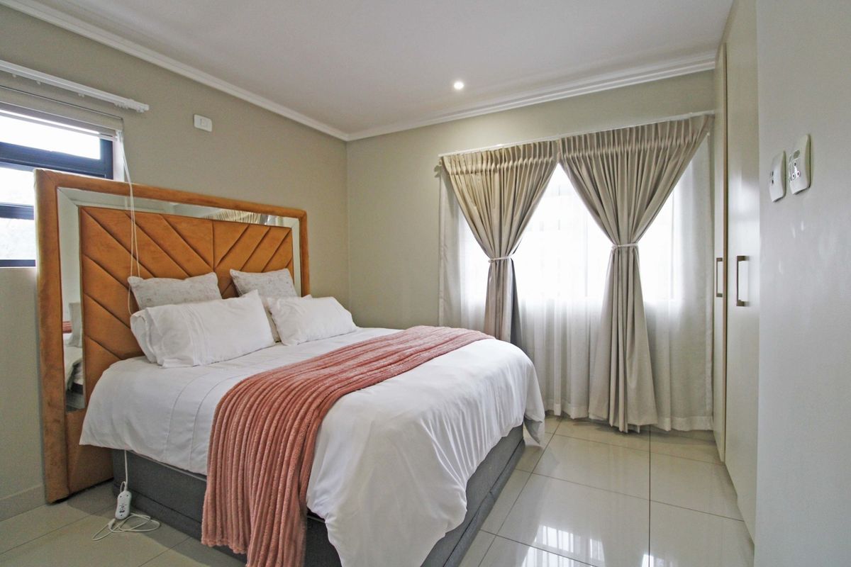 A well-maintained bedroom featuring neutral tiled flooring, built-in cupboards, and recessed ceiling lighting, offering a clean and functional living space.