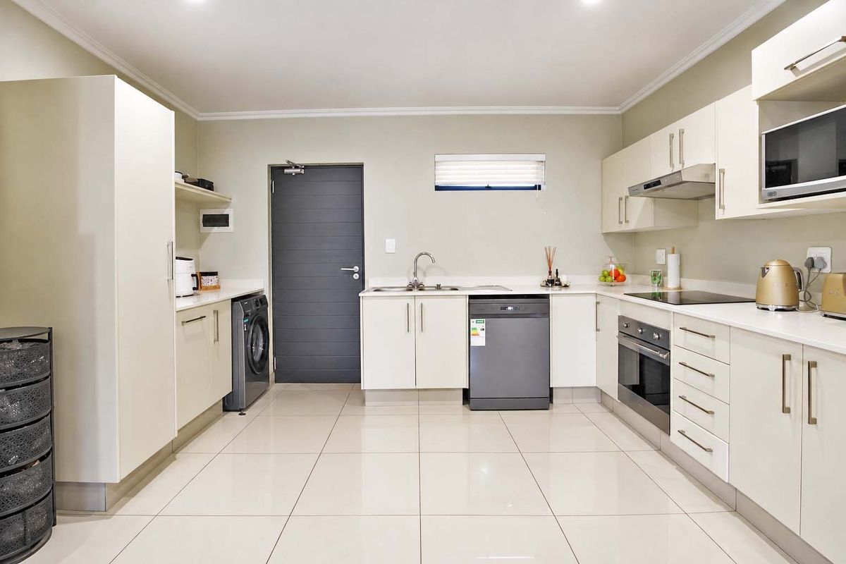 Modern kitchen featuring white cabinetry, integrated appliances, sleek countertops, tiled flooring, and recessed lighting in a clean, functional layout.