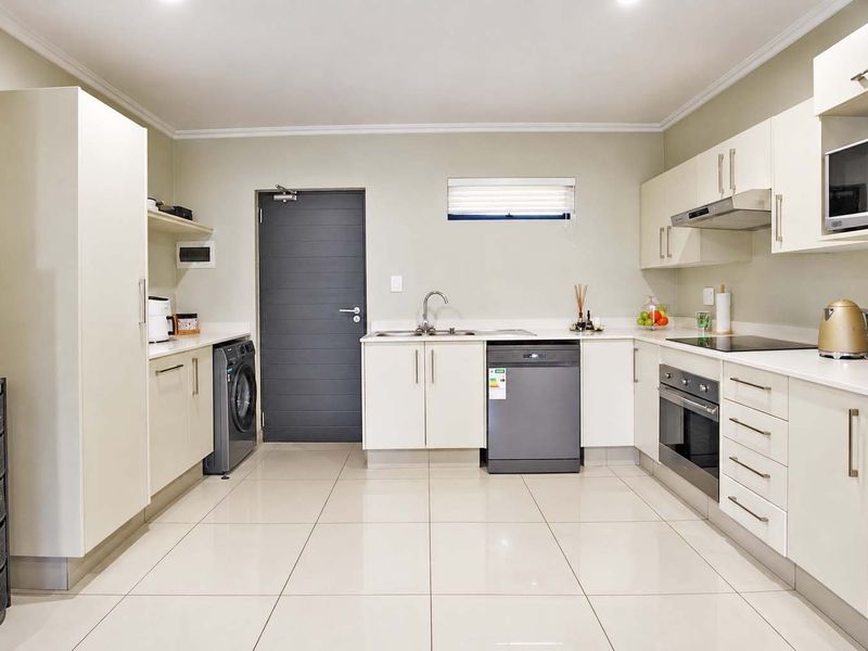 Modern kitchen featuring white cabinetry, integrated appliances, sleek countertops, tiled flooring, and recessed lighting in a clean, functional layout.