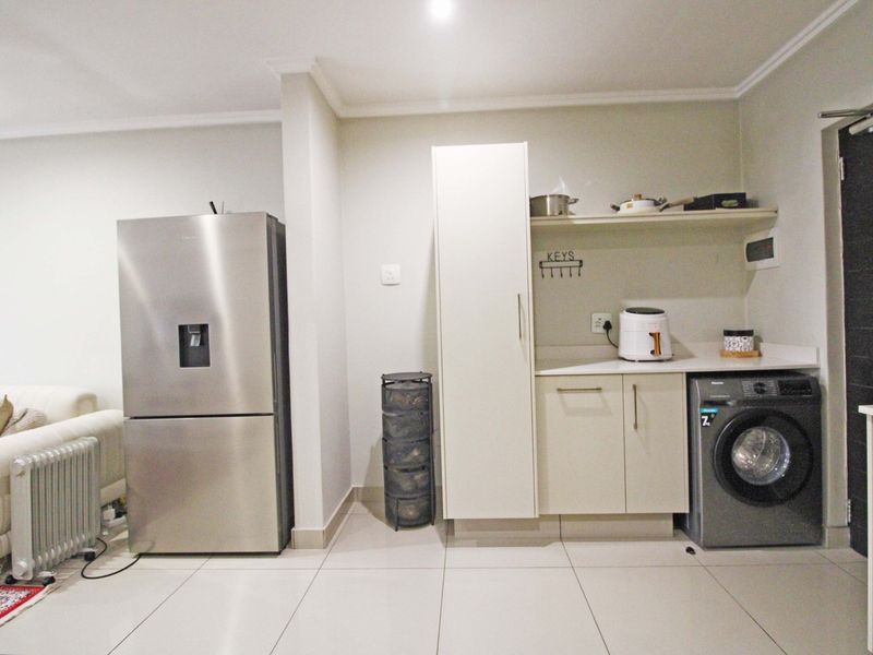 A functional scullery or utility area featuring built-in cabinetry, countertop space, and a dedicated connection for a washing machine.