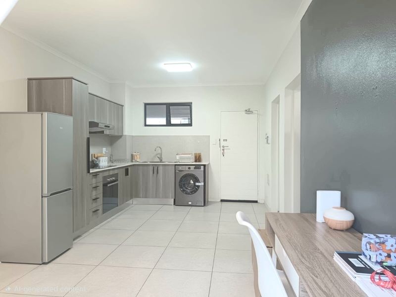 Modern open-plan kitchen featuring sleek grey cabinetry, built-in oven, extractor fan, and tiled flooring, seamlessly integrated with the living area.