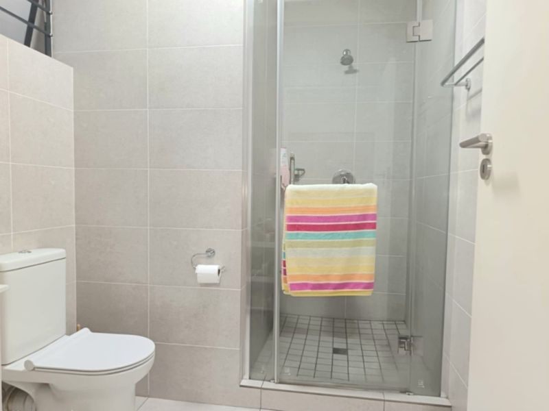 A modern bathroom featuring a glass-enclosed shower, neutral wall tiling, and a standard toilet suite.