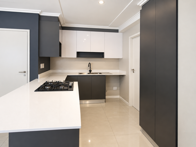 Modern kitchen featuring sleek two-tone cabinetry, quartz countertops, a gas hob, and high-quality tiled flooring in a clean, contemporary layout.