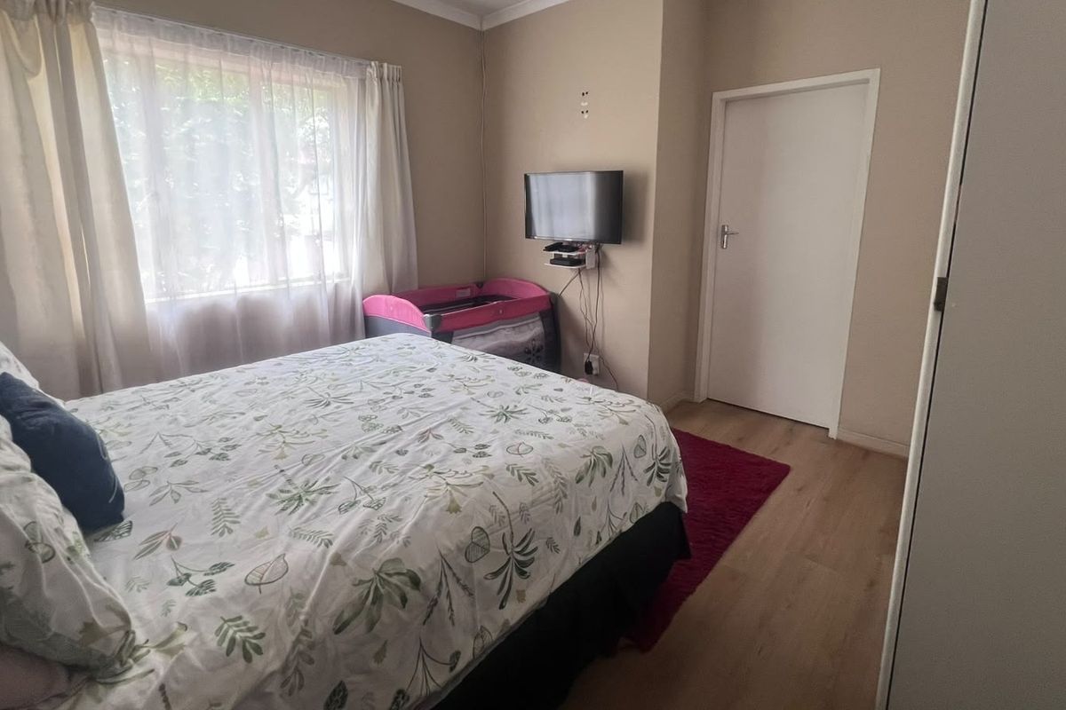 A functional bedroom featuring laminate flooring, a built-in wardrobe, and neutral wall tones, providing a comfortable and practical living space.
