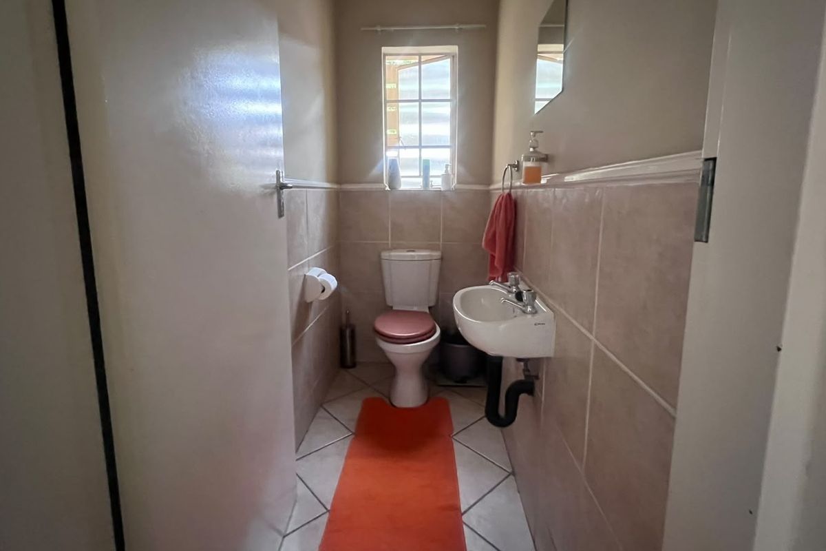 A compact guest bathroom featuring a wall-mounted basin, toilet, and neutral ceramic tiling throughout.
