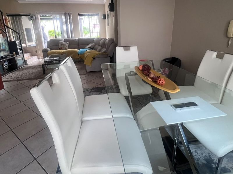 Open plan living and dining area featuring tiled flooring, a staircase with wrought iron railing, and sliding glass doors leading to the patio.