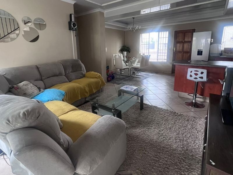 Open-plan living and dining area featuring tiled flooring, a kitchen island, and a coffered ceiling, creating a functional and connected living space.