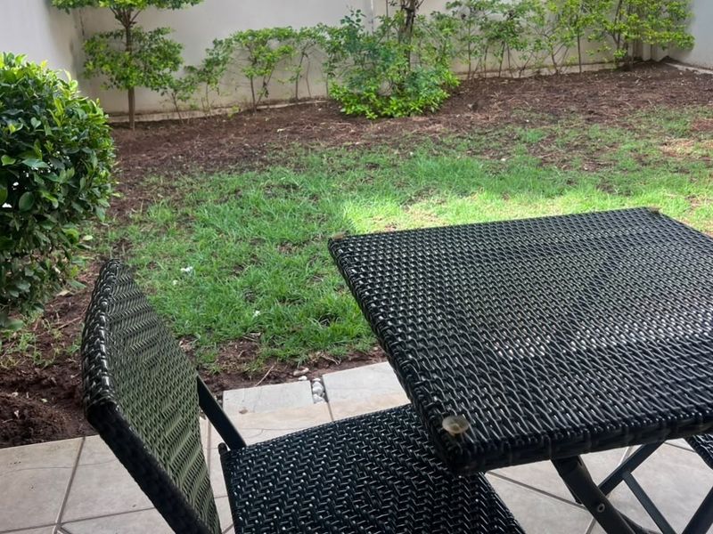 A private patio area featuring tiled flooring, overlooking a small landscaped garden space.