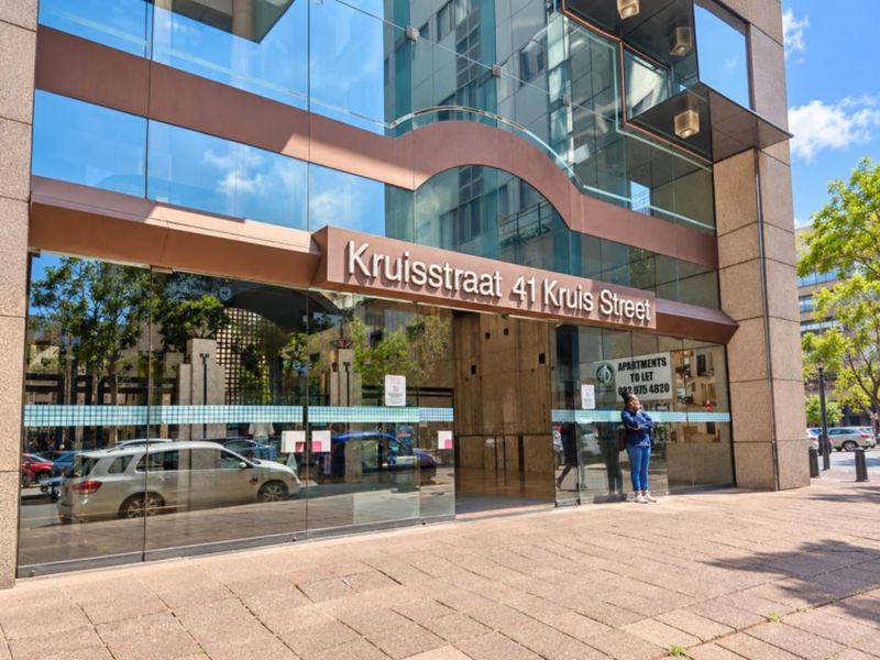 Modern apartment building entrance featuring a glass facade and paved street-level access at 41 Kruis Street.