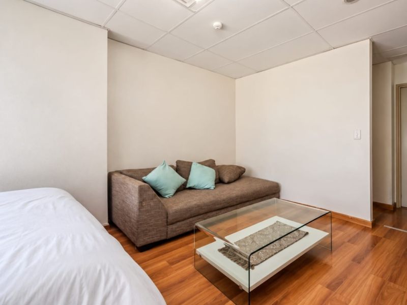 A bedroom featuring laminate flooring and a suspended ceiling with recessed lighting.