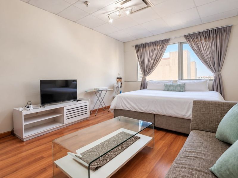 A spacious bedroom featuring laminate flooring, a suspended ceiling, and a large window providing natural light.