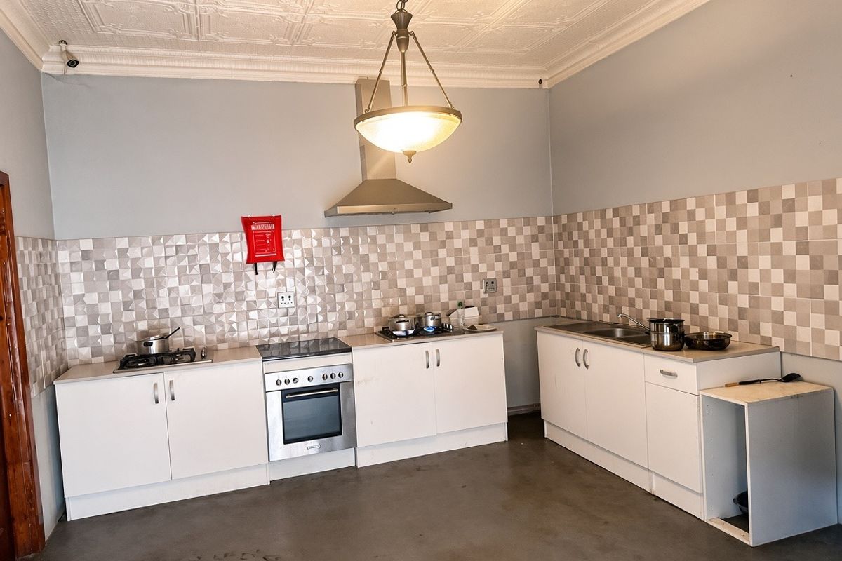 Functional kitchen featuring white cabinetry, stainless steel appliances, gas hob, extractor fan, and decorative ceiling tiles with a tiled splashback.