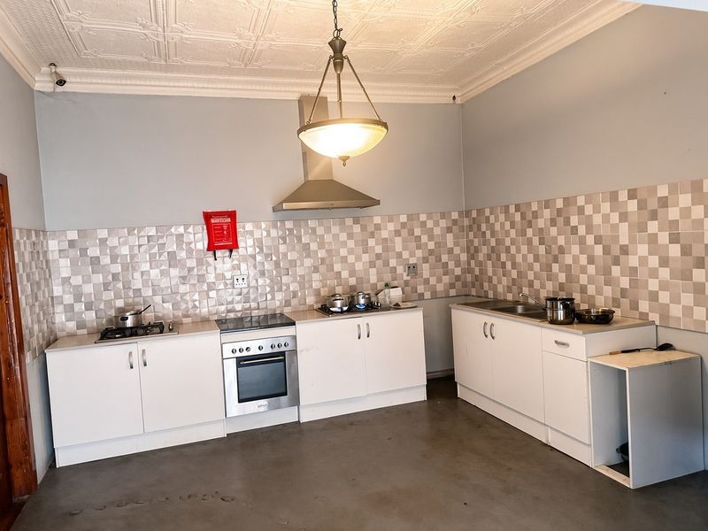 Functional kitchen featuring white cabinetry, stainless steel appliances, gas hob, extractor fan, and decorative ceiling tiles with a tiled splashback.