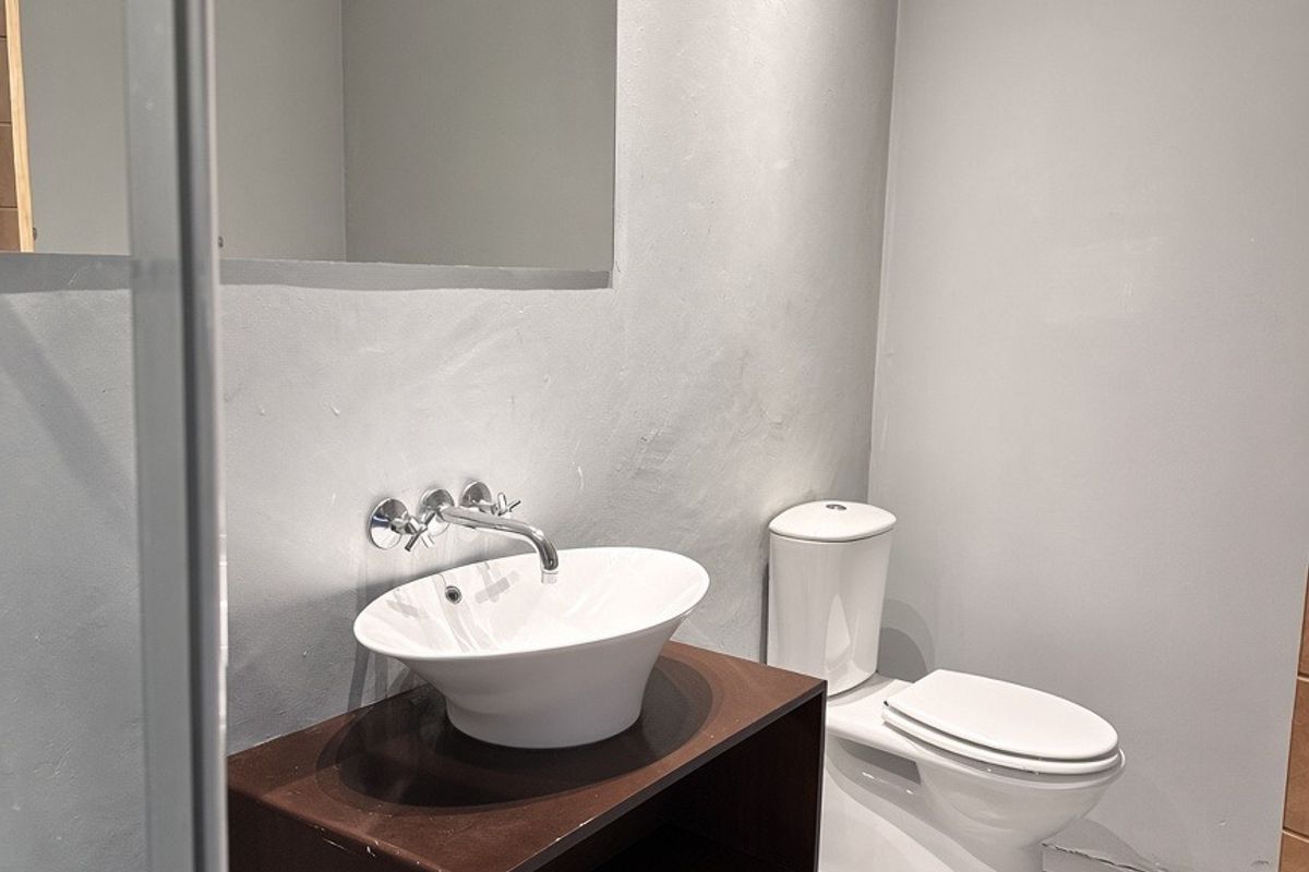 Modern bathroom featuring a floating vanity with a vessel sink, wall-mounted faucet, and a decorative framed mirror.