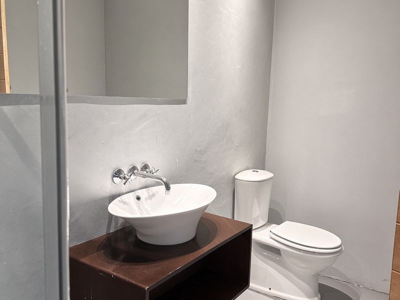 Modern bathroom featuring a floating vanity with a vessel sink, wall-mounted faucet, and a decorative framed mirror.