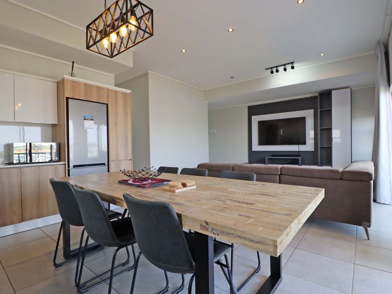 Modern open-plan living and dining area featuring contemporary cabinetry, recessed lighting, a built-in media wall, and large sliding doors leading to outdoor space.