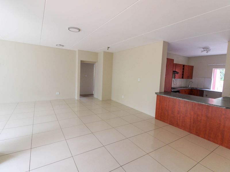 Spacious open-plan living area featuring tiled floors and a functional kitchen with built-in cabinetry and a breakfast bar.