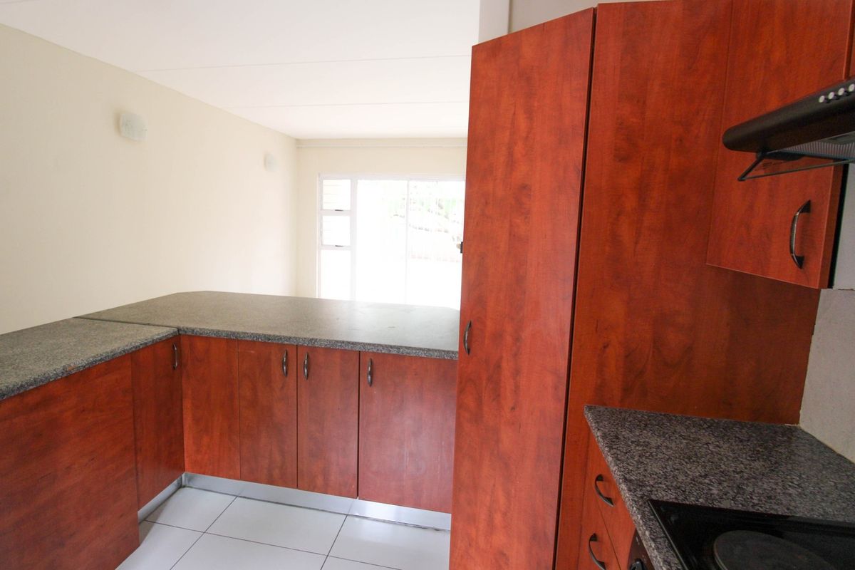 A functional kitchen featuring wood-look laminate cabinetry, granite countertops, and ceramic floor tiles, offering a clean and practical workspace.