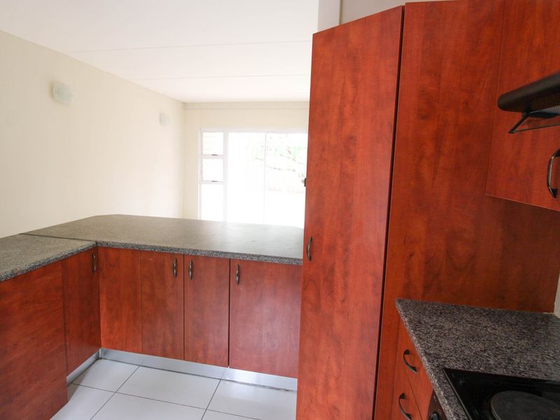 A functional kitchen featuring wood-look laminate cabinetry, granite countertops, and ceramic floor tiles, offering a clean and practical workspace.