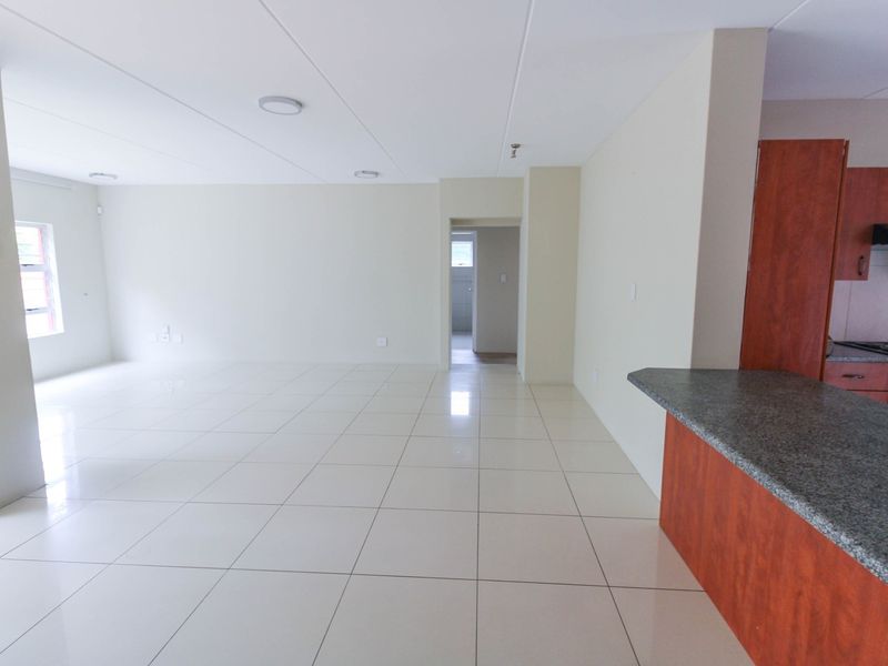 Spacious open-plan living area featuring tiled floors and a modern kitchen with granite countertops, built-in oven, and hob.