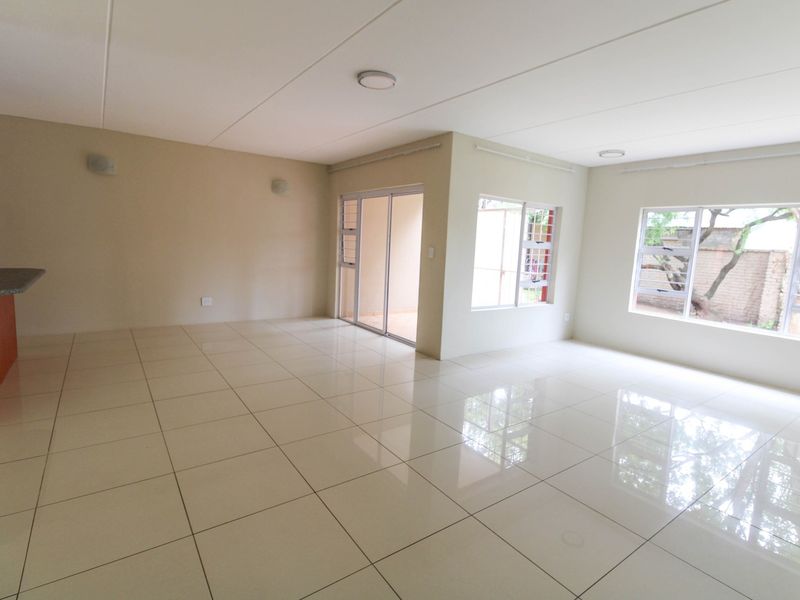 Spacious open-plan living area featuring polished tiled flooring, large windows for natural light, and a breakfast counter, offering a clean and versatile layout.