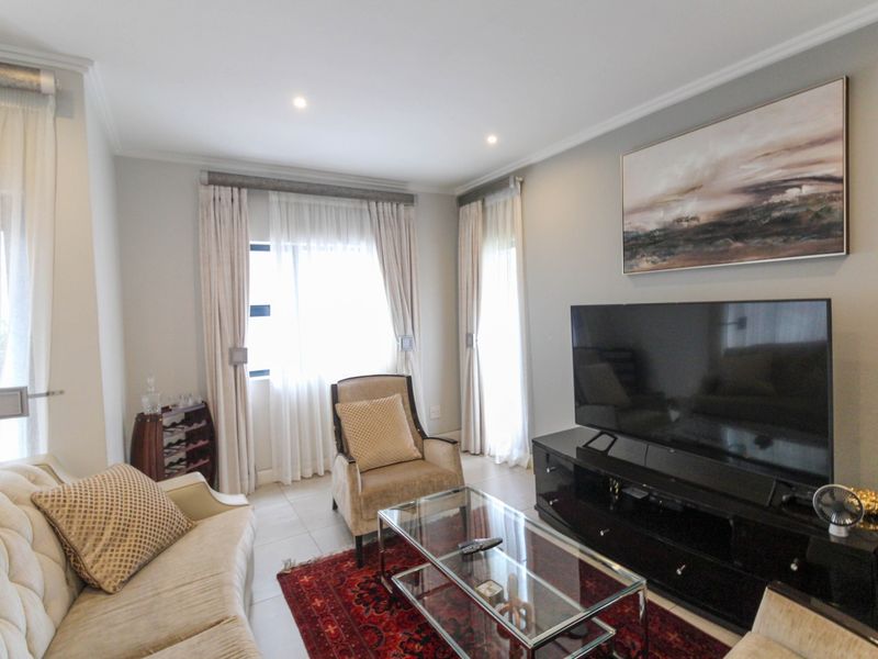 A well-maintained living room featuring neutral wall tones, tiled flooring, and recessed downlighting, creating a comfortable and inviting space.