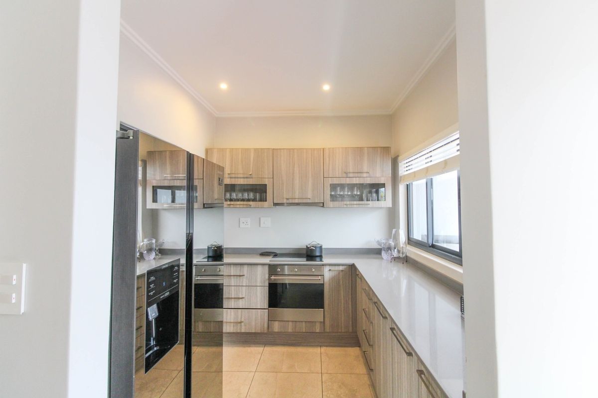 Modern kitchen featuring wood-finish cabinetry, stone countertops, integrated appliances, and tiled flooring, offering a clean and functional workspace.