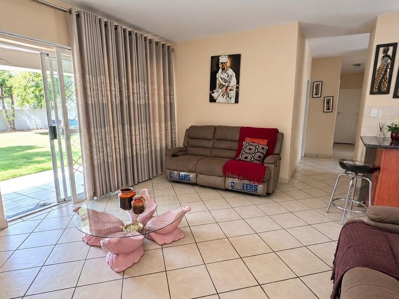 Open plan living area featuring tiled floors and a sliding glass door leading to the patio, seamlessly connected to a functional kitchen space.