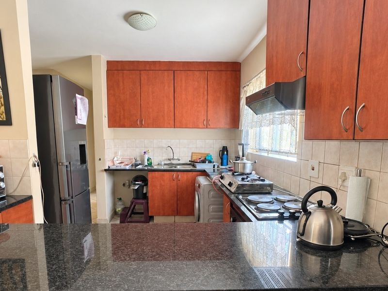 A functional kitchen featuring granite countertops, wood-finish cabinetry, a built-in hob, and an extractor fan, providing a practical workspace for daily cooking.