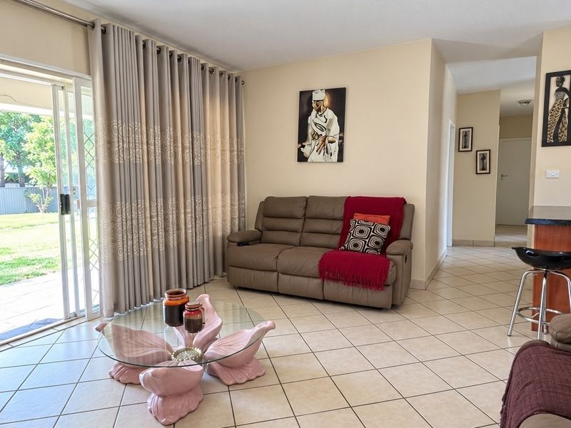 Open plan living area featuring ceramic floor tiles, a breakfast bar, and large sliding glass doors providing access to the rear garden.