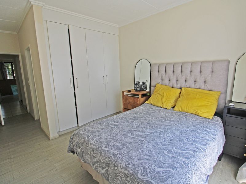 A well-lit bedroom featuring built-in cupboards and light-toned laminate flooring, providing a clean and functional living space.