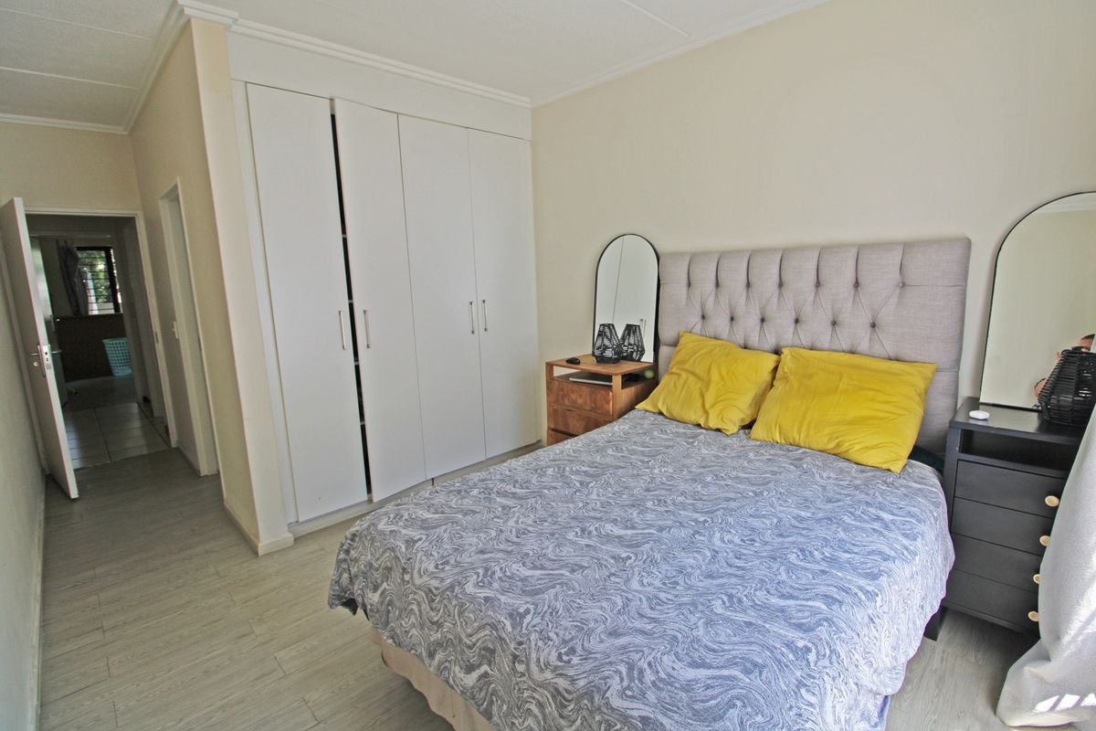 A well-lit bedroom featuring built-in cupboards and light-toned laminate flooring, providing a clean and functional living space.