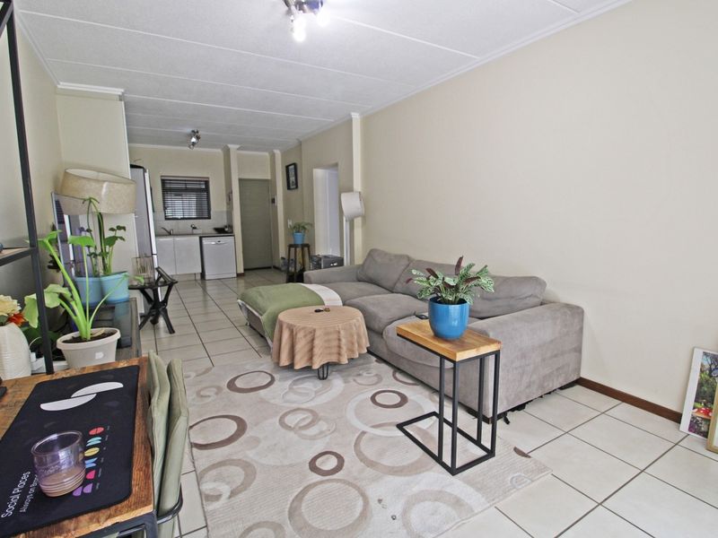 Open-plan living area featuring tiled flooring throughout, connecting the lounge space to a functional kitchen area with built-in cabinetry.