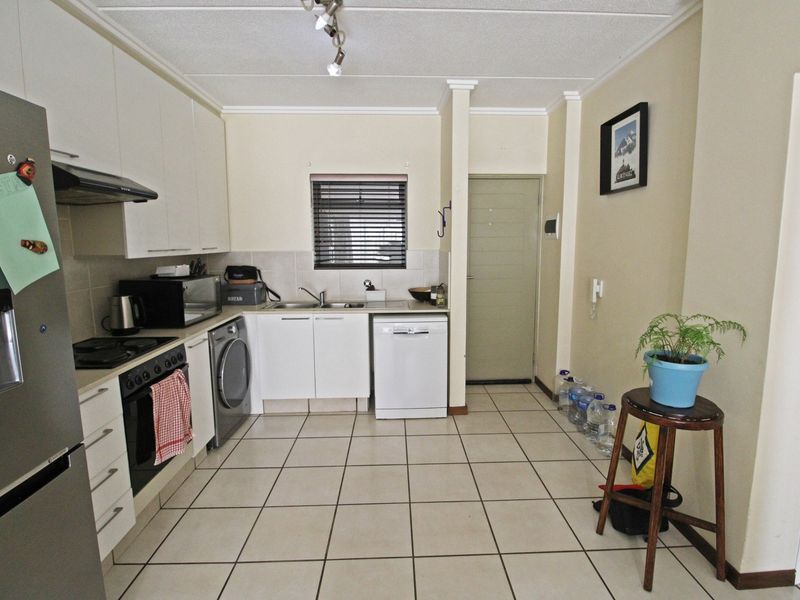 A functional kitchen featuring white cabinetry, tiled flooring, a built-in oven with extractor fan, and a tiled backsplash.
