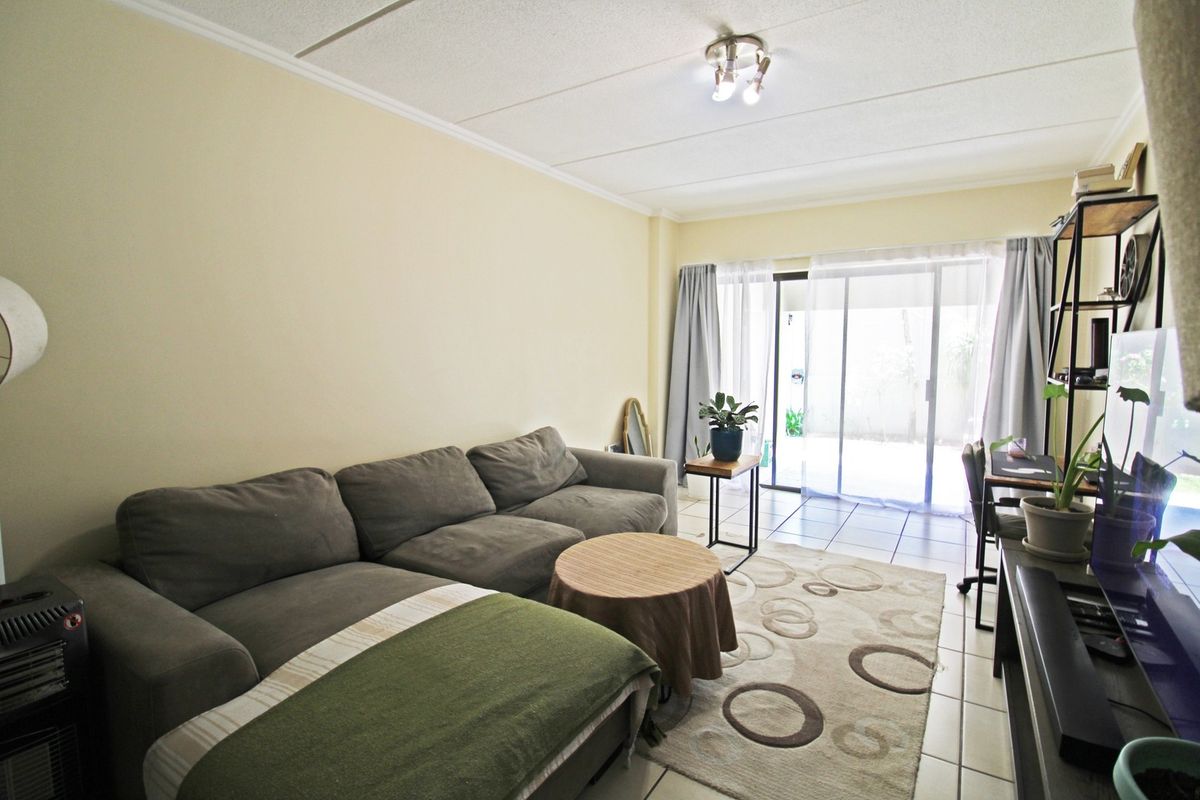 A comfortable living room featuring tiled flooring and a large sliding glass door that provides access to the outdoor area.
