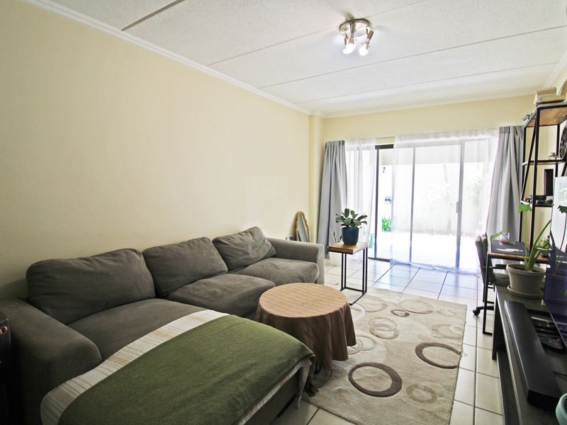 A comfortable living room featuring tiled flooring and a large sliding glass door that provides access to the outdoor area.