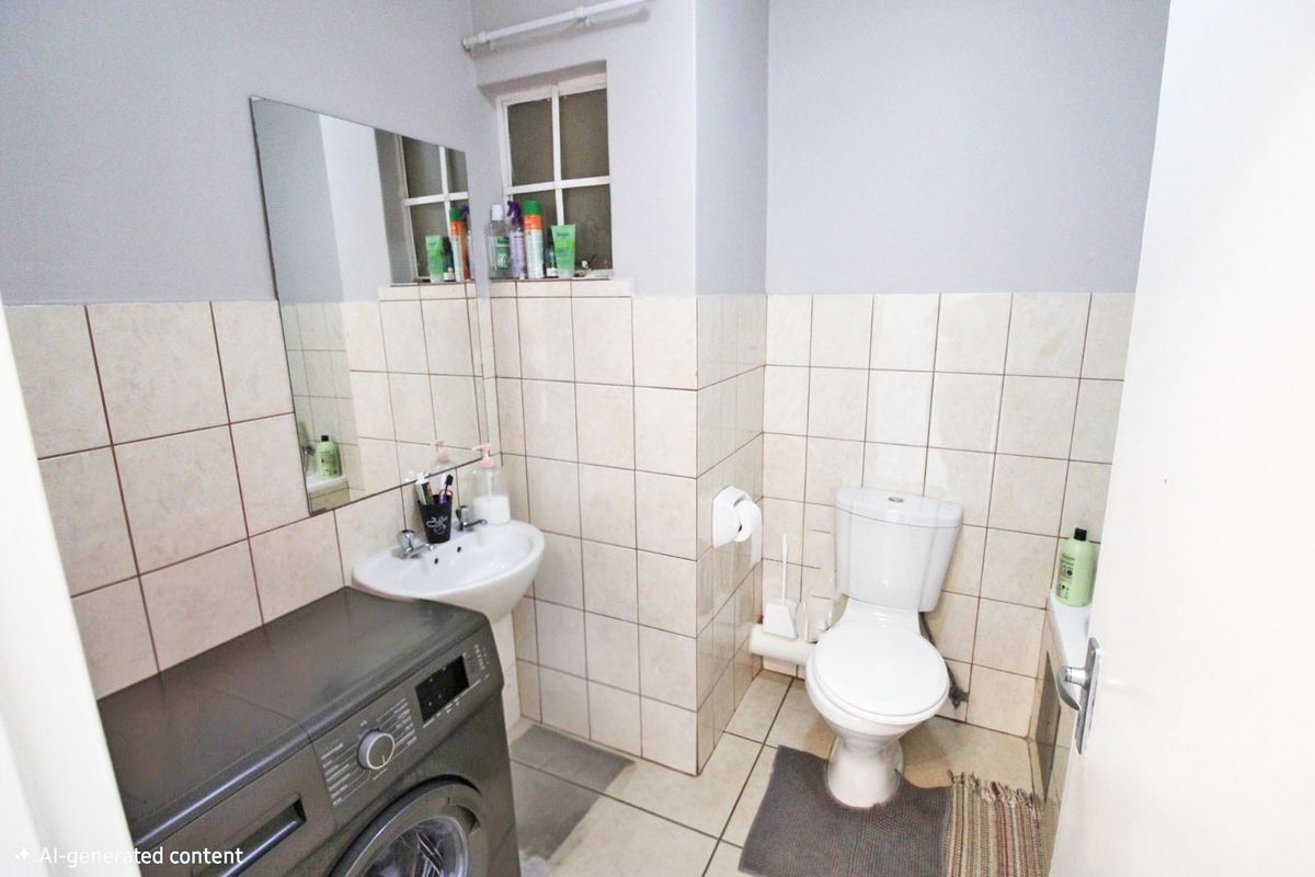 A functional bathroom featuring a pedestal basin, toilet, and tiled finishes, providing a practical layout for daily use.