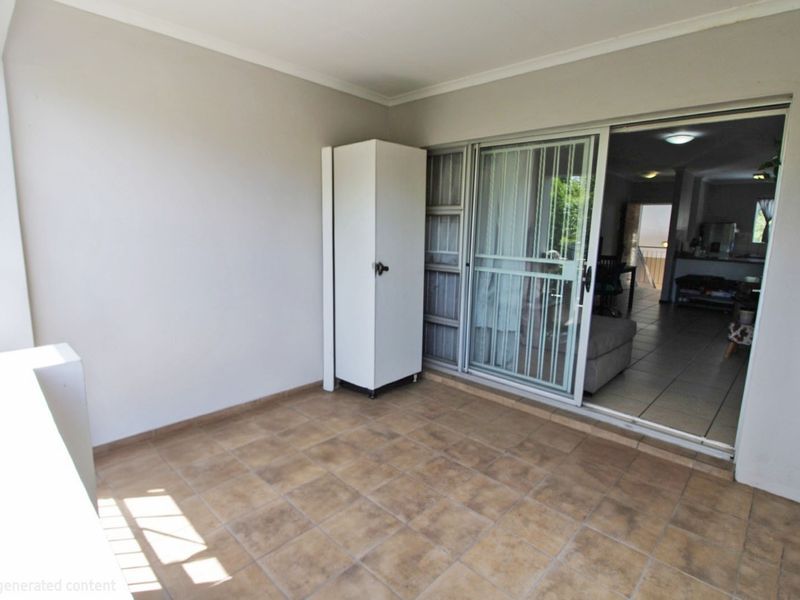 A covered balcony featuring tiled flooring, a built-in storage cupboard, and sliding glass door access to the interior living area.