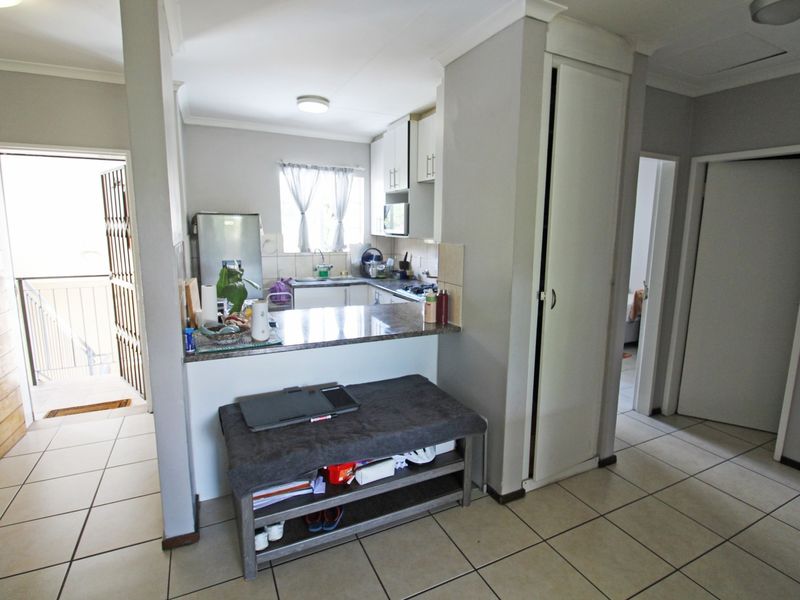 Open plan kitchen area featuring granite countertops and built-in cabinetry, with tiled flooring and direct access to the entrance and hallway.