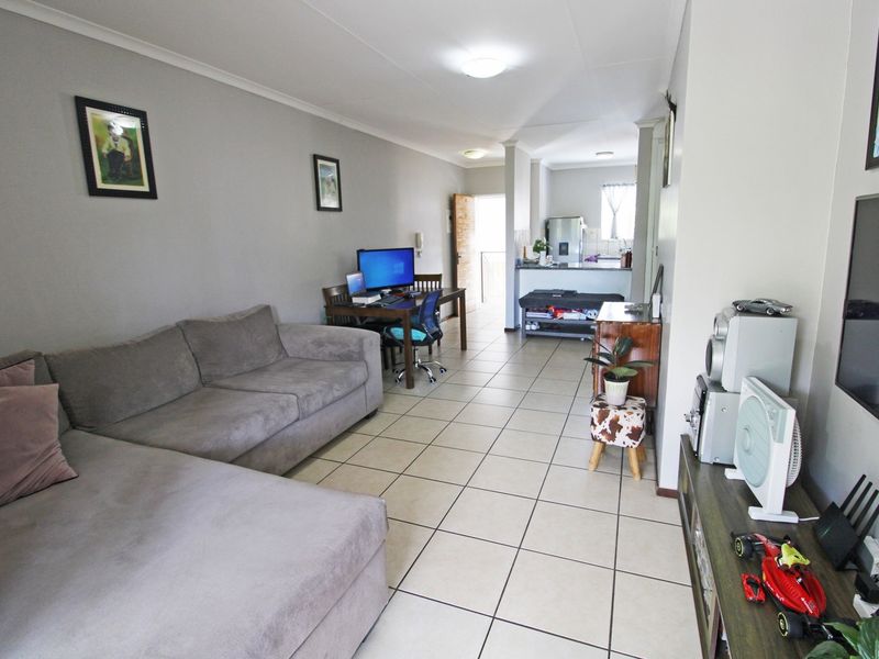 Open plan living area featuring tiled flooring and a connected kitchen space with a breakfast bar.