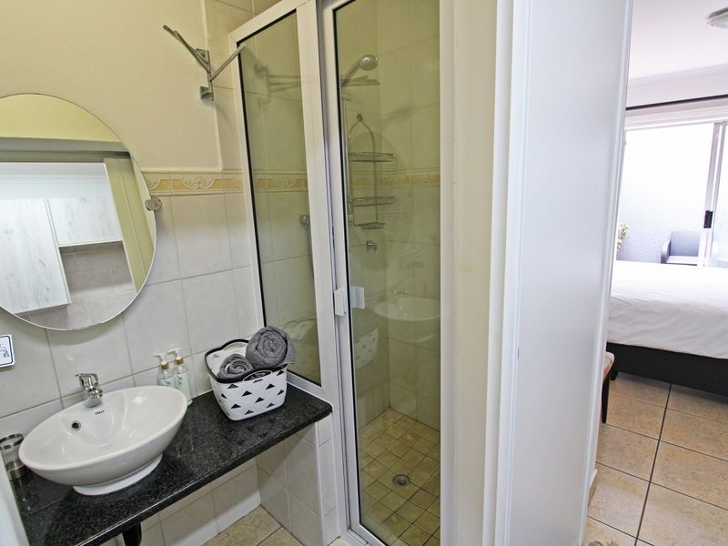 Compact bathroom featuring a vessel sink on a granite vanity, a glass-enclosed shower, and tiled flooring, with direct access to the adjacent bedroom.
