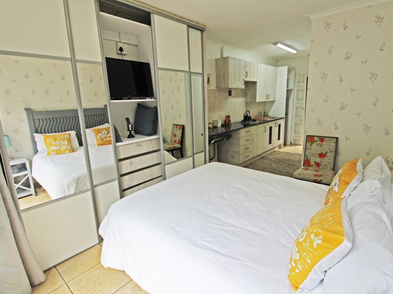 Open-plan studio cottage featuring a combined bedroom and kitchen area with built-in mirrored wardrobes and functional kitchen cabinetry.