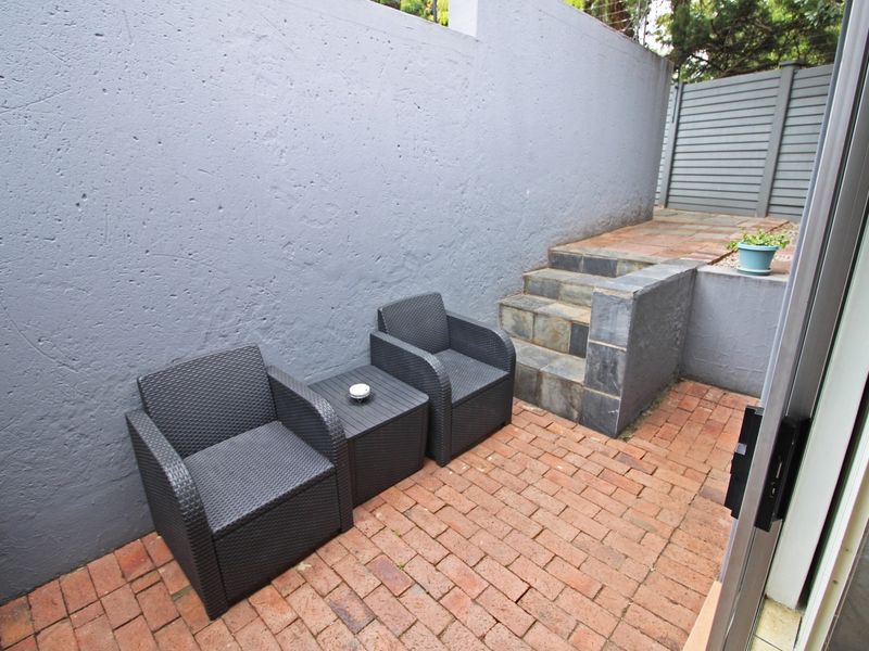 A private outdoor patio area featuring brick paving, stone steps, and a high boundary wall, providing a secluded space for relaxation.